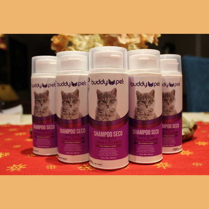 Fila de botes de Shampoo en Seco para Gatos Buddy Pet presentados sobre un fondo decorativo, subrayando la disponibilidad de este esencial de higiene felina que ayuda a mantener el manto fresco y saludable.